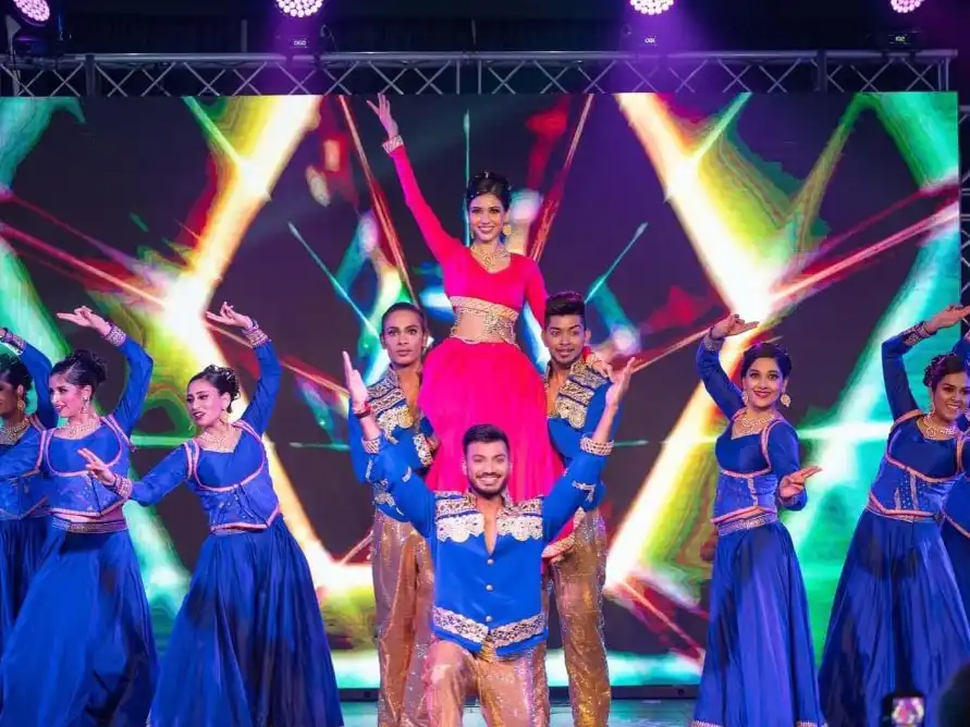 Dancer performing a Bollywood item under magenta stage lighting