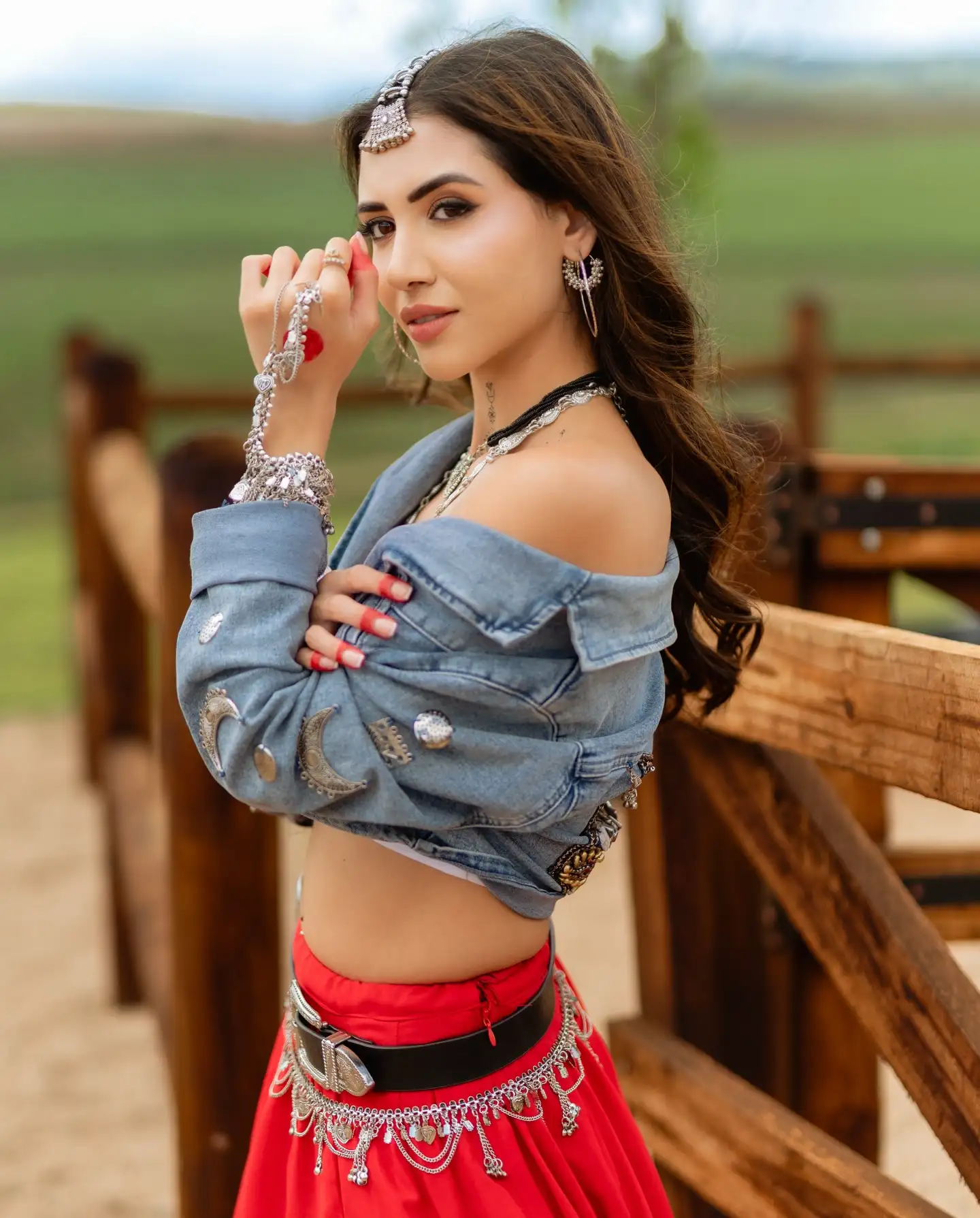 Divaksha Jinabhai looking at the camera over her shoulder, in a denim jacket and silver jewellery