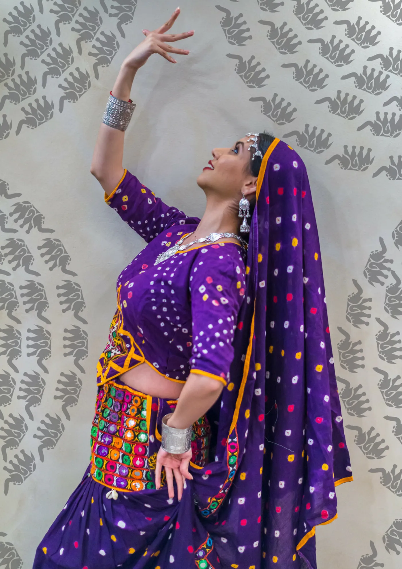 Divaksha in a purple bandhani lehenga, one arm raised in a classical pose