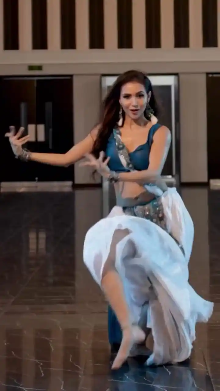 Divaksha Jinabhai mid-dance in a blue top and flowing white skirt on a polished ballroom floor