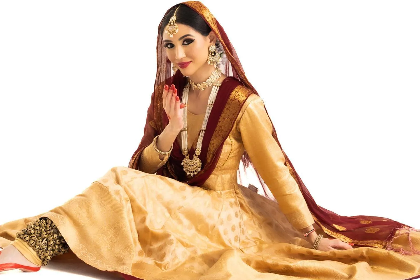 Divaksha in a gold and maroon bridal lehenga, seated, ghungroo at her ankle